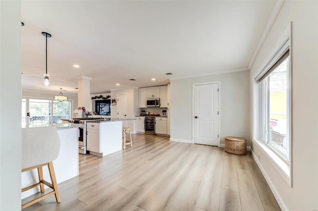 kitchen featuring white cabinets, stainless steel appliances, hanging light fixtures, and a breakfast bar area