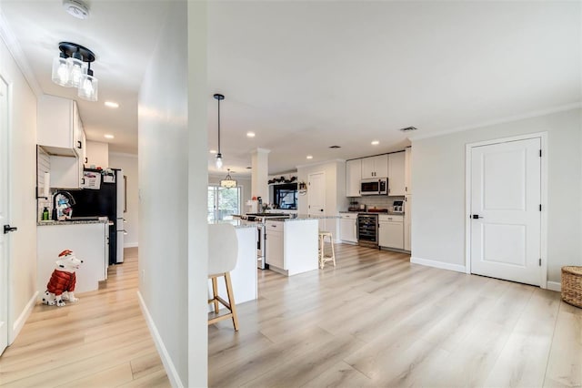 kitchen with appliances with stainless steel finishes, backsplash, white cabinets, a center island, and a breakfast bar