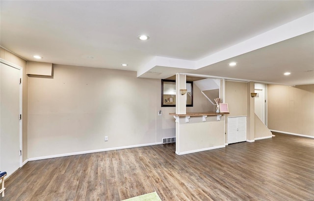 interior space featuring kitchen peninsula, a kitchen breakfast bar, and dark hardwood / wood-style flooring