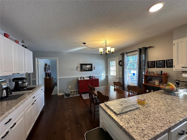 kitchen featuring sink, white cabinetry, pendant lighting, a notable chandelier, and dark wood-type flooring