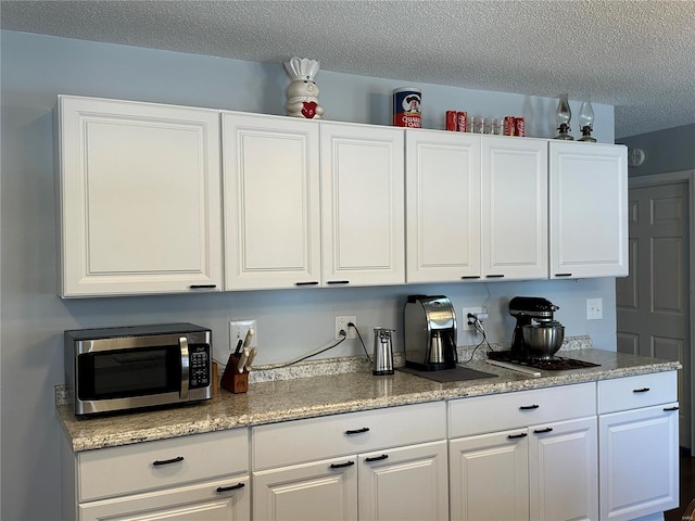 bar with white cabinets and a textured ceiling