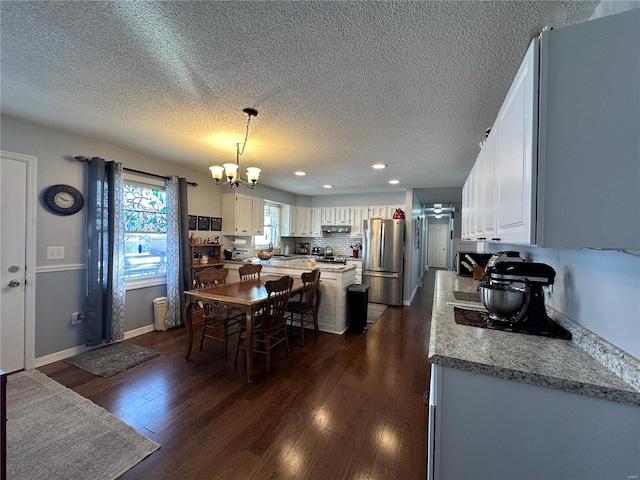 dining room with a textured ceiling, a notable chandelier, and dark hardwood / wood-style floors