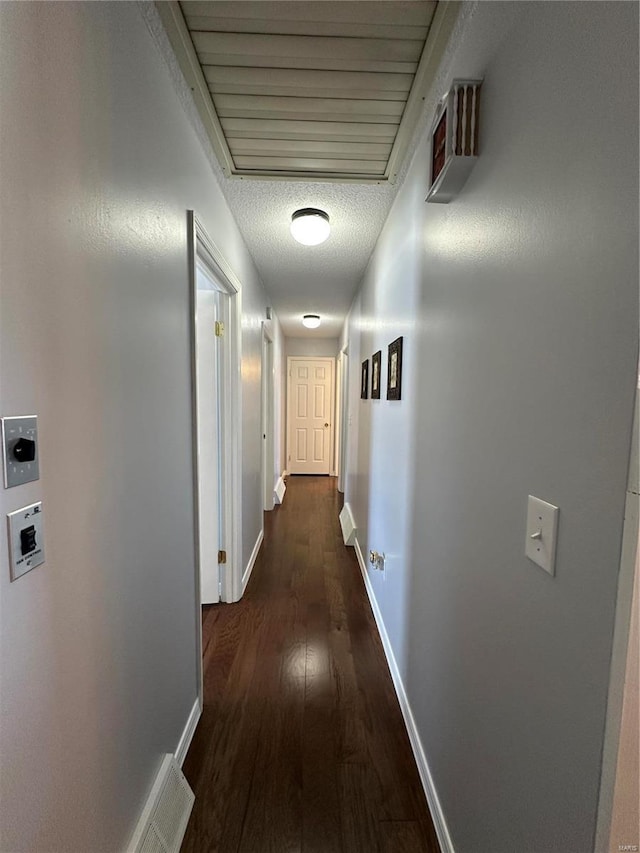 hallway with a textured ceiling and dark hardwood / wood-style floors