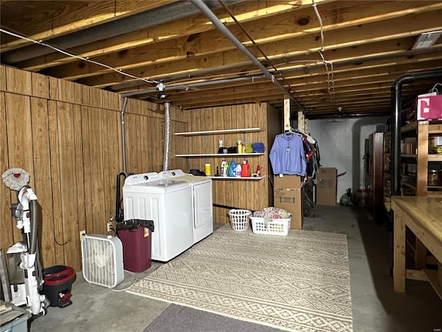 basement with wood walls and washing machine and clothes dryer