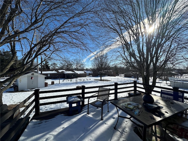 snow covered deck featuring a shed and grilling area