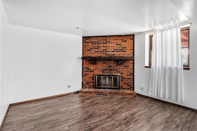 unfurnished living room featuring a brick fireplace and hardwood / wood-style flooring