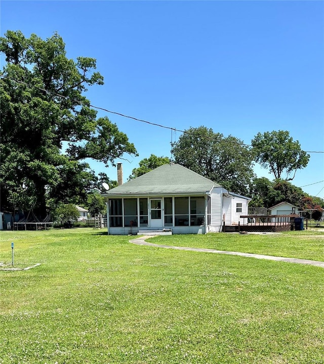 view of front of home with a trampoline, a front lawn, and a sunroom