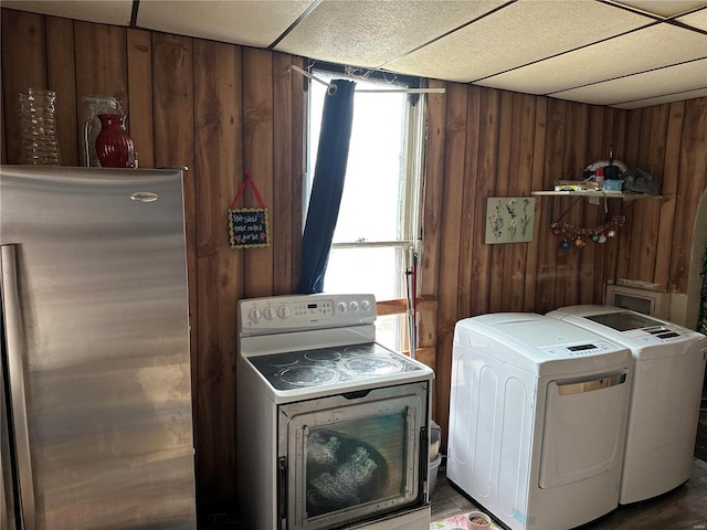 laundry area with wooden walls and washer and clothes dryer