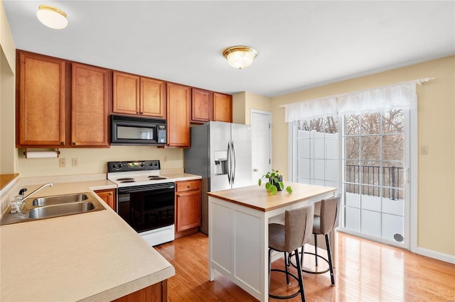 kitchen featuring a kitchen breakfast bar, light wood-type flooring, sink, electric range, and a center island