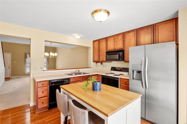 kitchen featuring sink, a notable chandelier, kitchen peninsula, pendant lighting, and black appliances