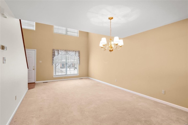 carpeted spare room featuring a notable chandelier