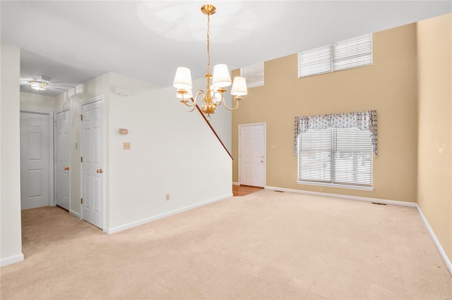 spare room featuring light carpet and a notable chandelier