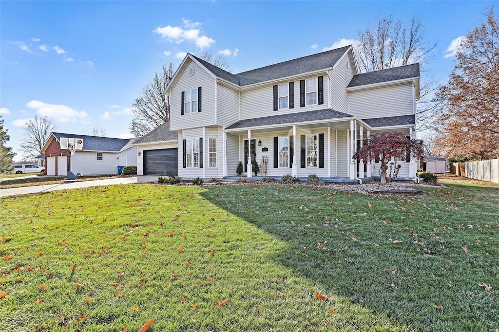 view of front facade with covered porch, a garage, and a front lawn