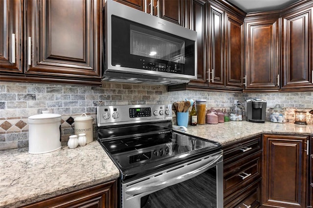 kitchen with dark brown cabinets, light stone counters, stainless steel appliances, and tasteful backsplash