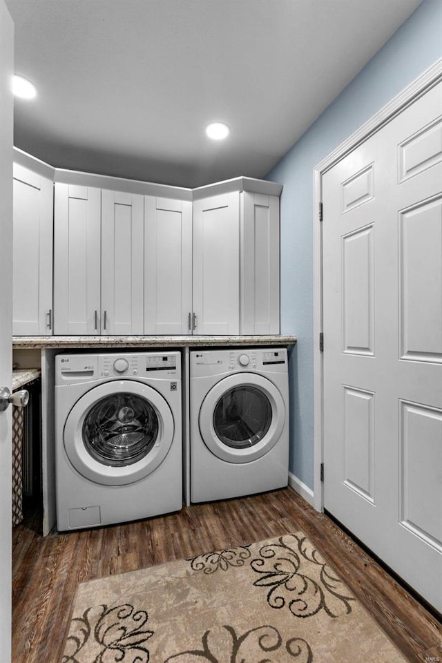 clothes washing area featuring cabinets, dark hardwood / wood-style floors, and washing machine and clothes dryer