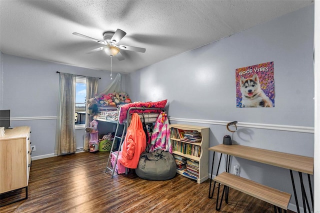 bedroom with a textured ceiling, ceiling fan, and dark wood-type flooring