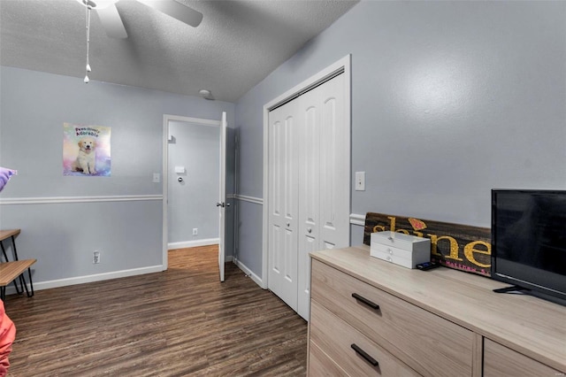 bedroom with ceiling fan, dark hardwood / wood-style floors, a textured ceiling, and a closet