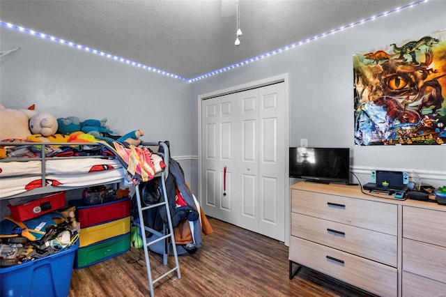 bedroom featuring a textured ceiling, ceiling fan, dark wood-type flooring, and a closet