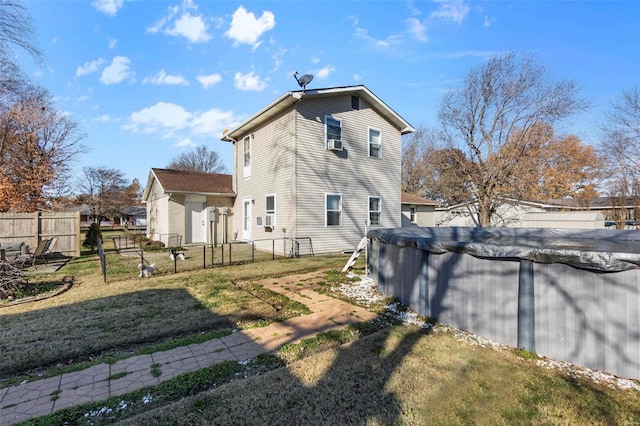 rear view of house featuring a lawn and a covered pool