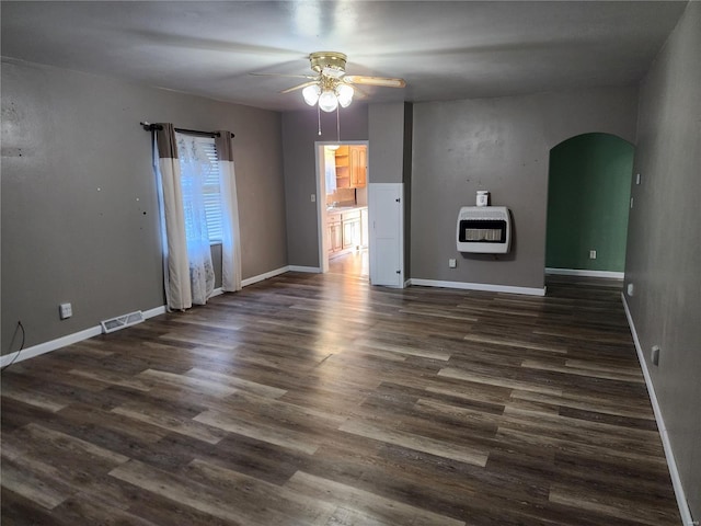 unfurnished room featuring dark hardwood / wood-style flooring, heating unit, and ceiling fan