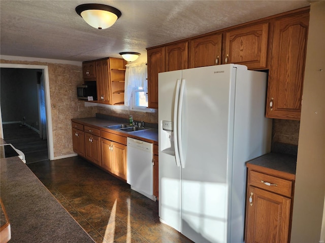 kitchen with a textured ceiling, sink, and white appliances