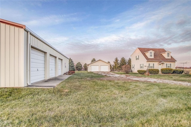 yard at dusk featuring a garage and an outdoor structure