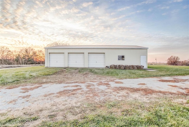 garage at dusk featuring a lawn