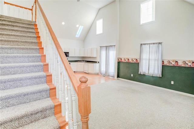 stairway with a skylight and high vaulted ceiling