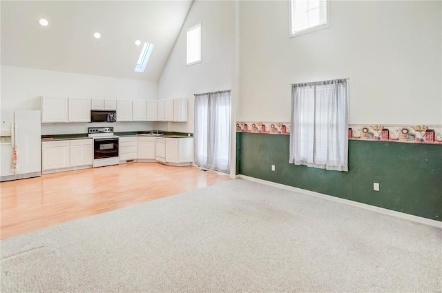 kitchen with white cabinets, white appliances, high vaulted ceiling, and a skylight