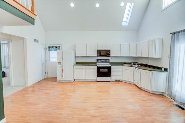 kitchen with a skylight, sink, high vaulted ceiling, white appliances, and white cabinets