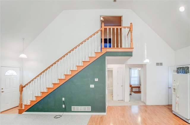 staircase with wood-type flooring and high vaulted ceiling