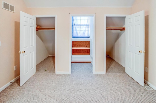 unfurnished bedroom featuring two closets and light colored carpet