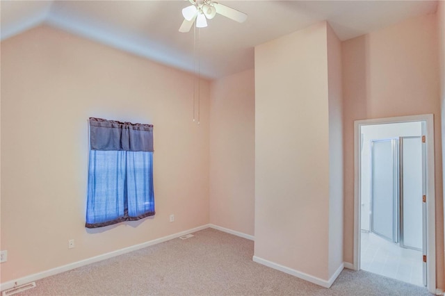 empty room featuring ceiling fan, light colored carpet, and lofted ceiling