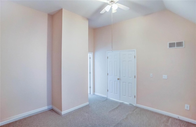 carpeted spare room with ceiling fan and vaulted ceiling