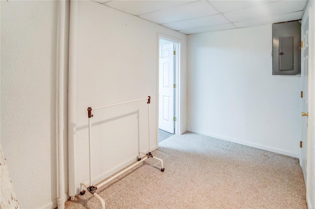 empty room featuring carpet, a drop ceiling, and electric panel