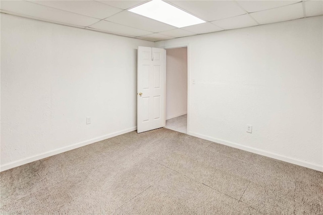 carpeted empty room featuring a drop ceiling