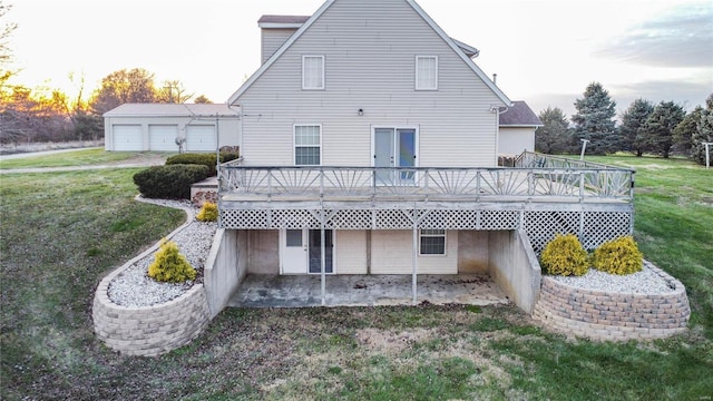 back house at dusk featuring a deck and a lawn