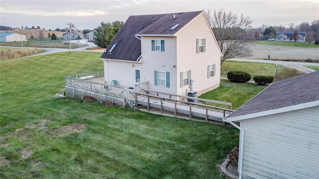 rear view of property with a lawn, cooling unit, and a deck