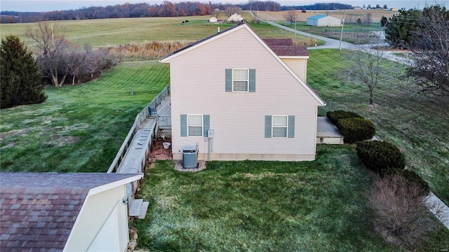 view of side of home featuring a rural view, central AC, and a lawn