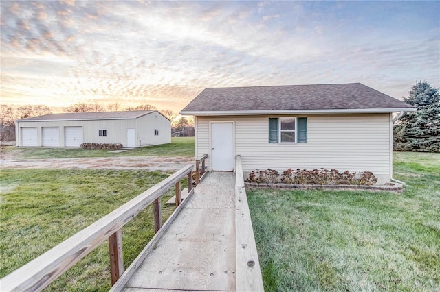 single story home with a lawn, an outbuilding, and a garage