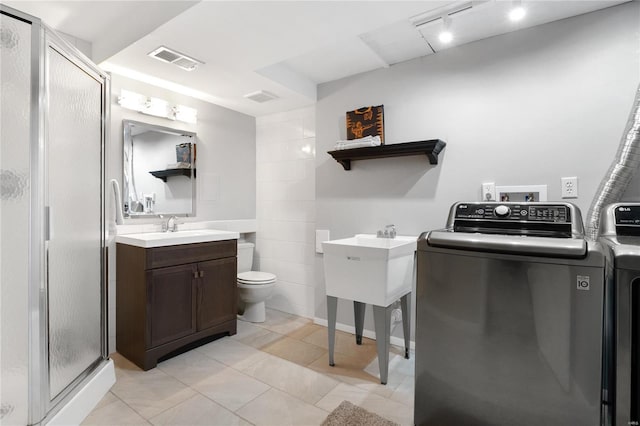 bathroom with vanity, tile patterned floors, toilet, an enclosed shower, and washing machine and clothes dryer