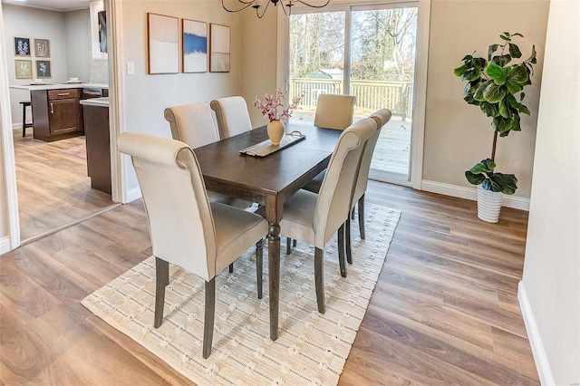 dining space featuring light hardwood / wood-style flooring and an inviting chandelier