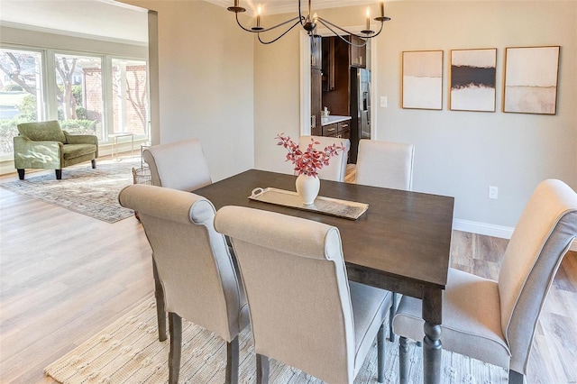 dining area with ornamental molding, a chandelier, and light wood-type flooring