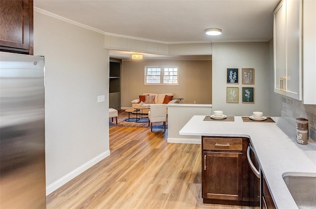 kitchen featuring ornamental molding, dark brown cabinets, stainless steel appliances, and light hardwood / wood-style floors