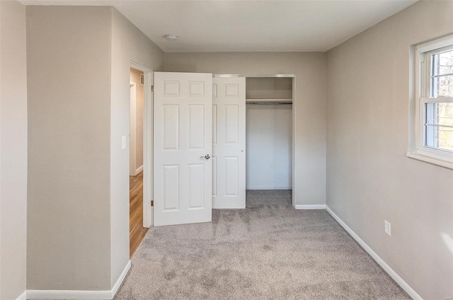 unfurnished bedroom featuring a closet and light colored carpet