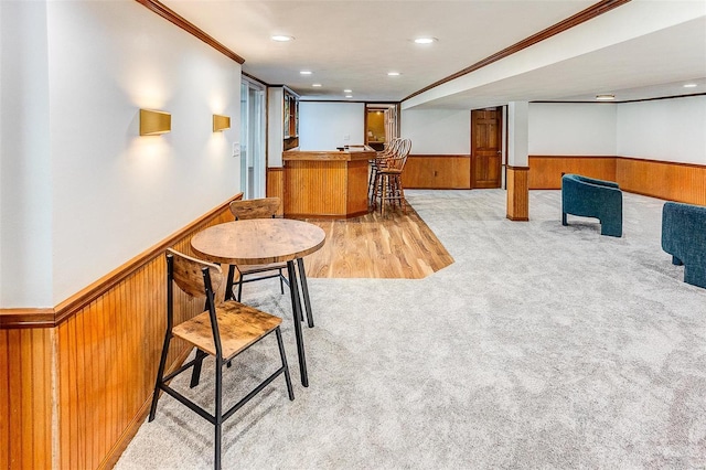 interior space featuring wooden walls, light carpet, and ornamental molding