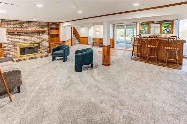 carpeted living room with crown molding, wood walls, indoor bar, and a brick fireplace