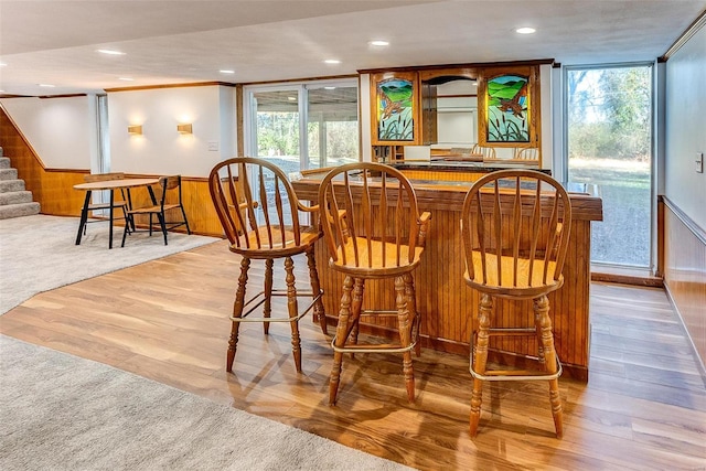 bar featuring light hardwood / wood-style flooring, plenty of natural light, and wood walls