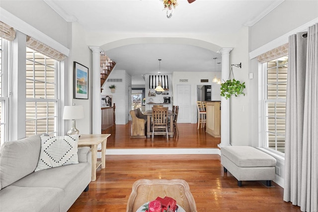 living room with hardwood / wood-style floors, crown molding, and decorative columns