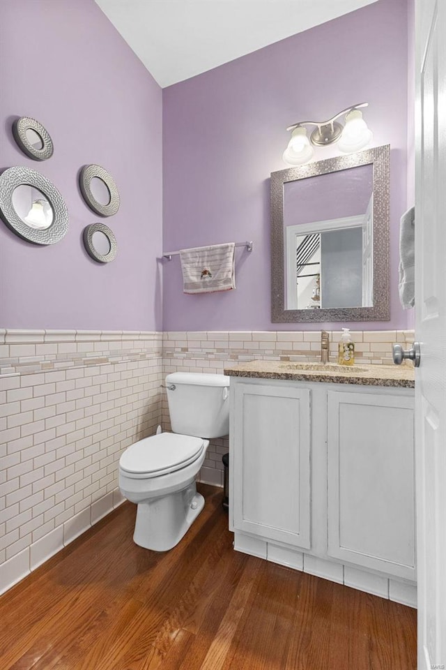 bathroom featuring toilet, vanity, tile walls, and hardwood / wood-style flooring